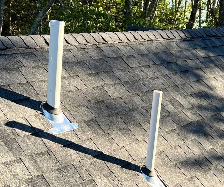 Two white pipes are sitting on top of a roof.