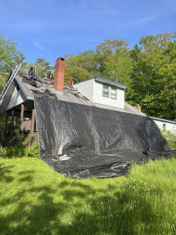 A house is being remodeled with a tarp on the roof.