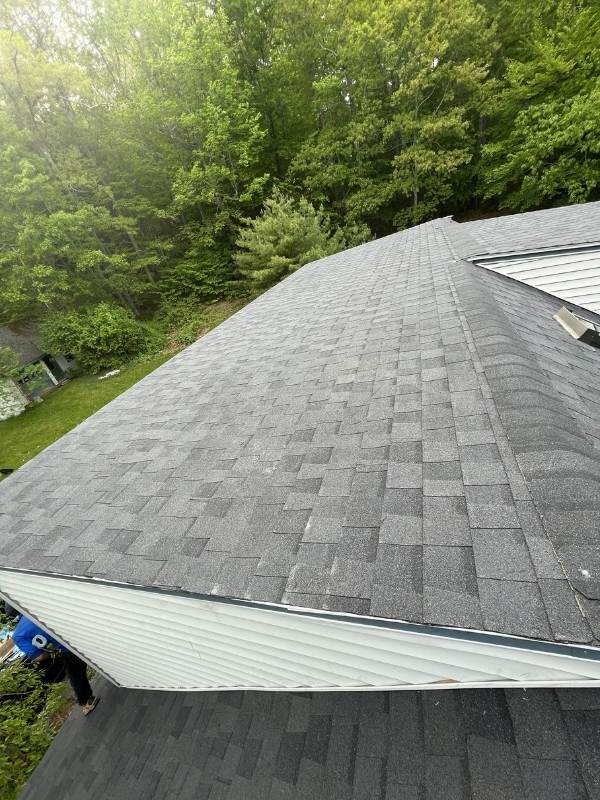 A roof with a lot of shingles on it is surrounded by trees.
