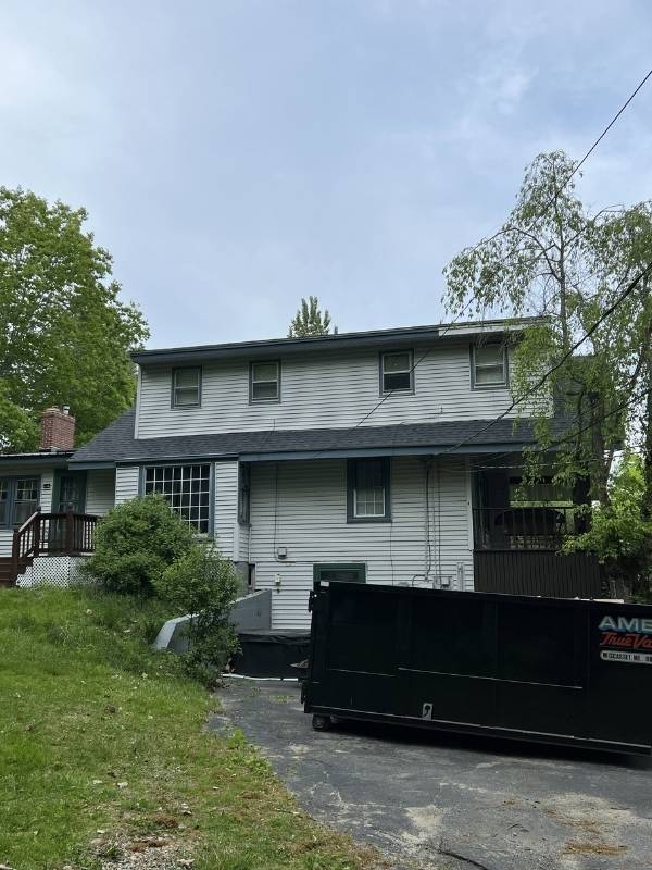 A large house with a black dumpster in front of it.