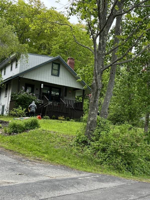 A man is standing in front of a house in the woods.