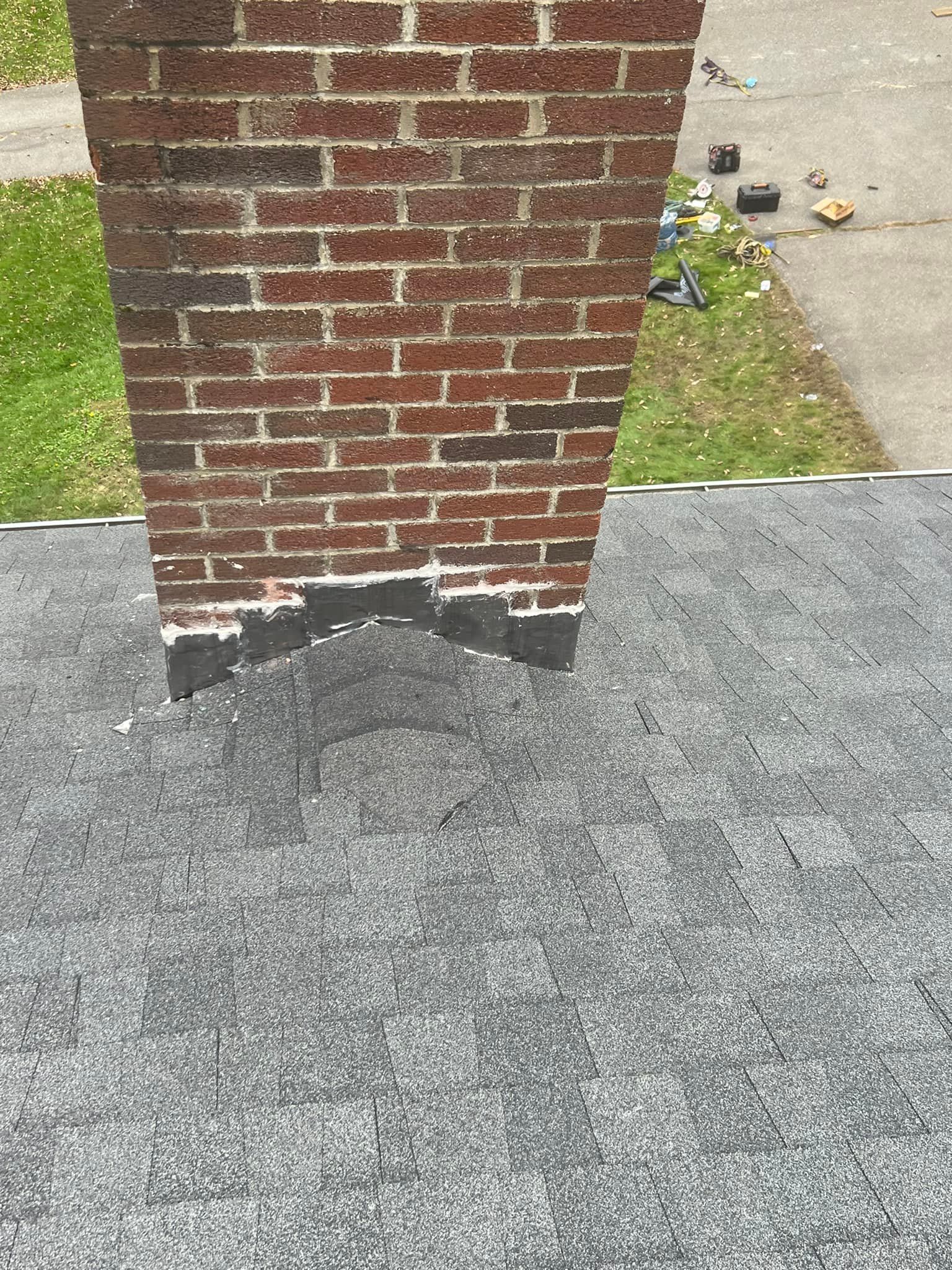 A brick chimney is sitting on top of a gray roof.