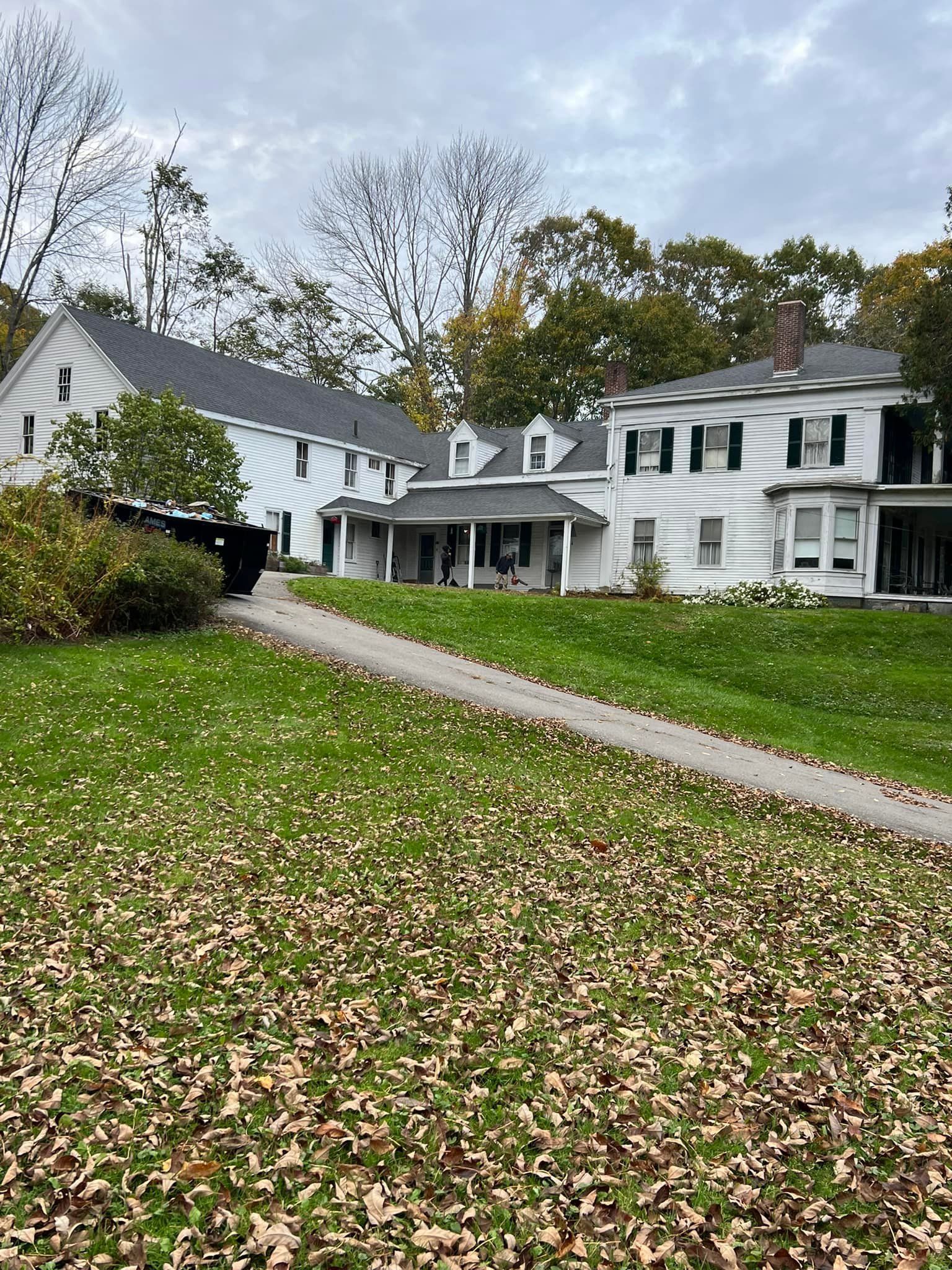 A large white house is sitting on top of a lush green hill.