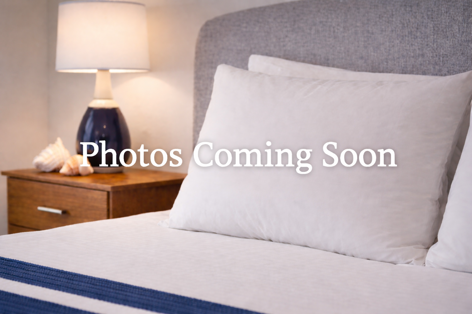 A white pillow rests on a bed next to a wooden nightstand with a lamp, with the text 