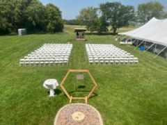 A large grassy field with rows of white chairs and a tent in the background.