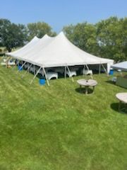 A large white tent is sitting in the middle of a lush green field.
