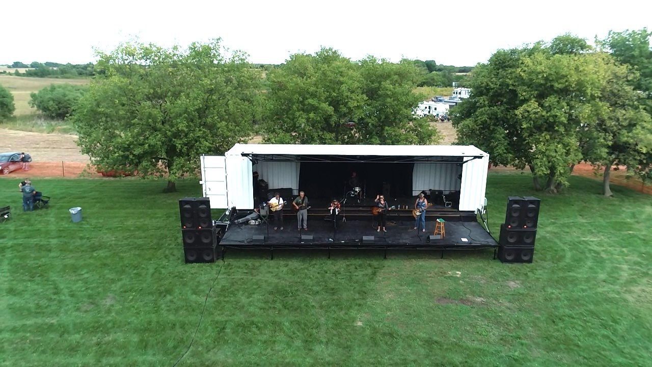 An aerial view of a stage set up in a grassy field.