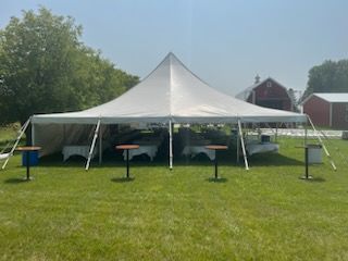 A large white tent is sitting in the middle of a grassy field.
