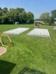 A row of white chairs are sitting on top of a lush green field.