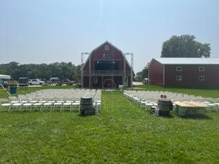 A wedding ceremony is taking place in front of a red barn.
