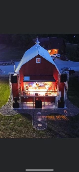 An aerial view of a red barn with a stage inside of it at night.