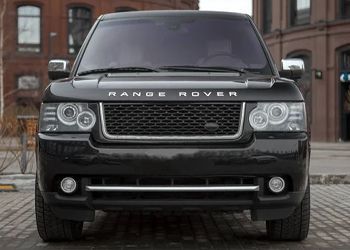 A black range rover is parked in front of a brick building.