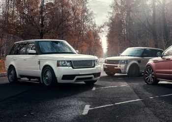 Three range rovers are parked on the side of a road.