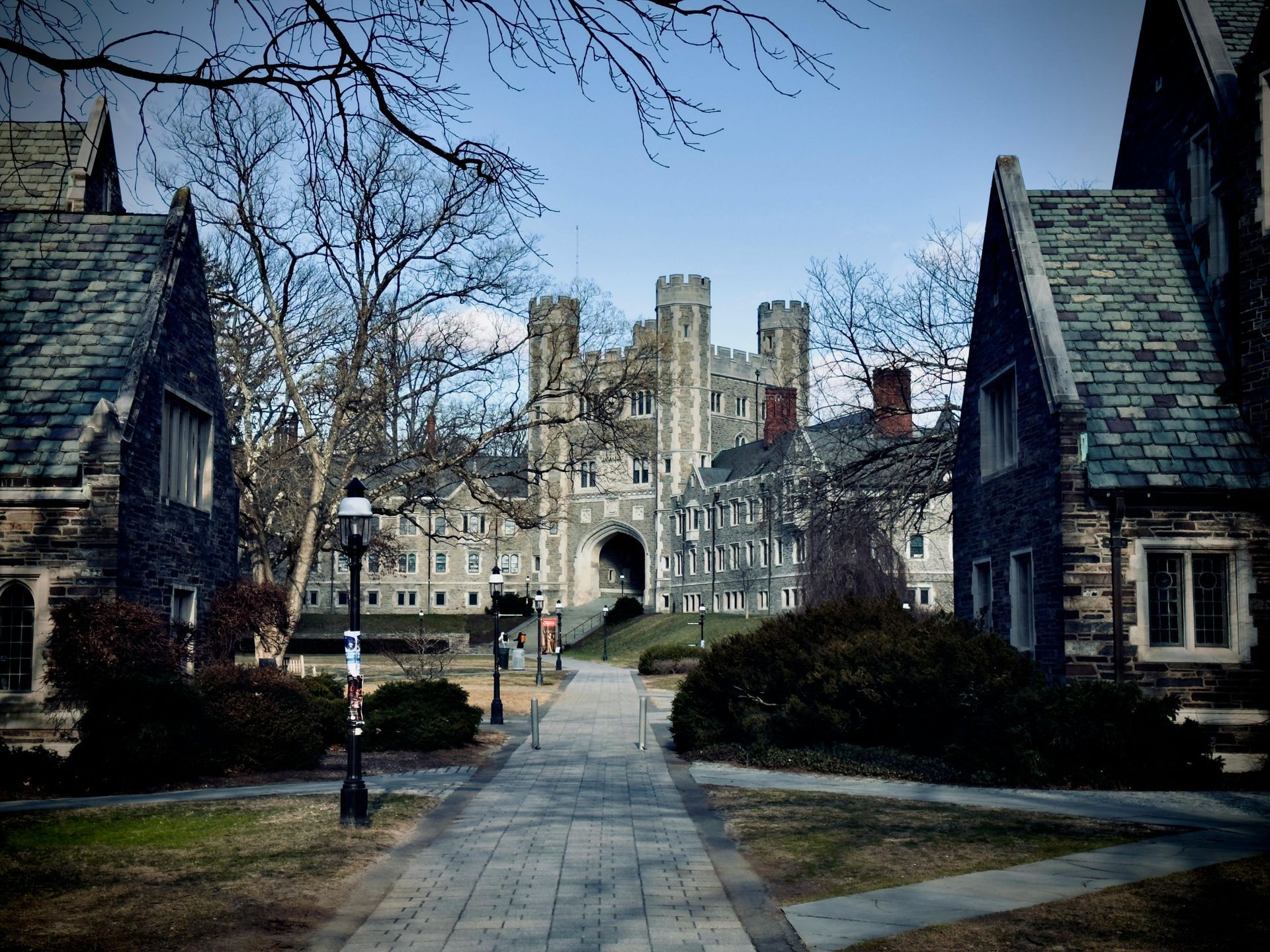 Gothic campus courtyard with stone buildings and a central tower under a cloudy sky