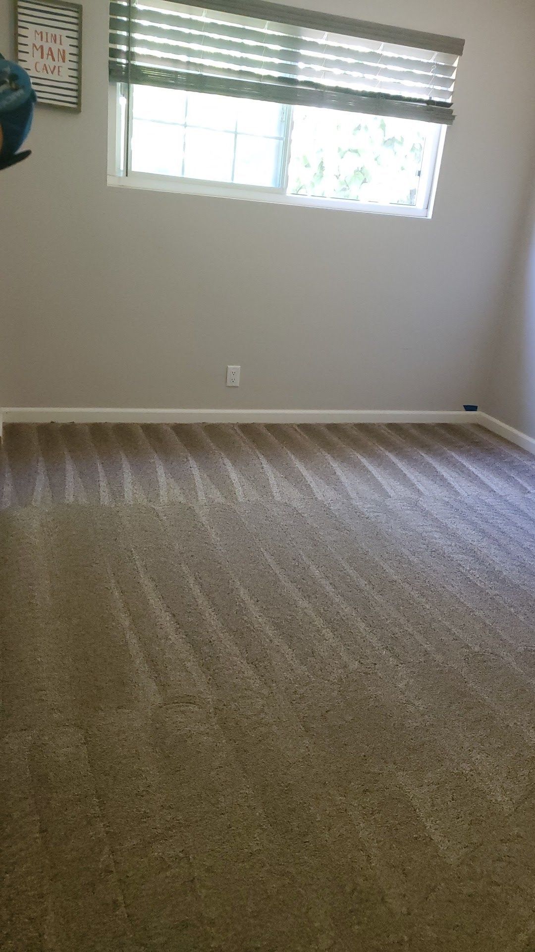 An empty room with a carpeted floor and a window.