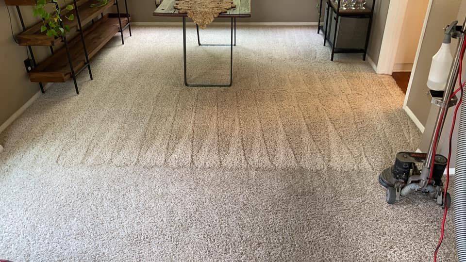 A carpeted floor in a living room with a table and a vacuum cleaner.