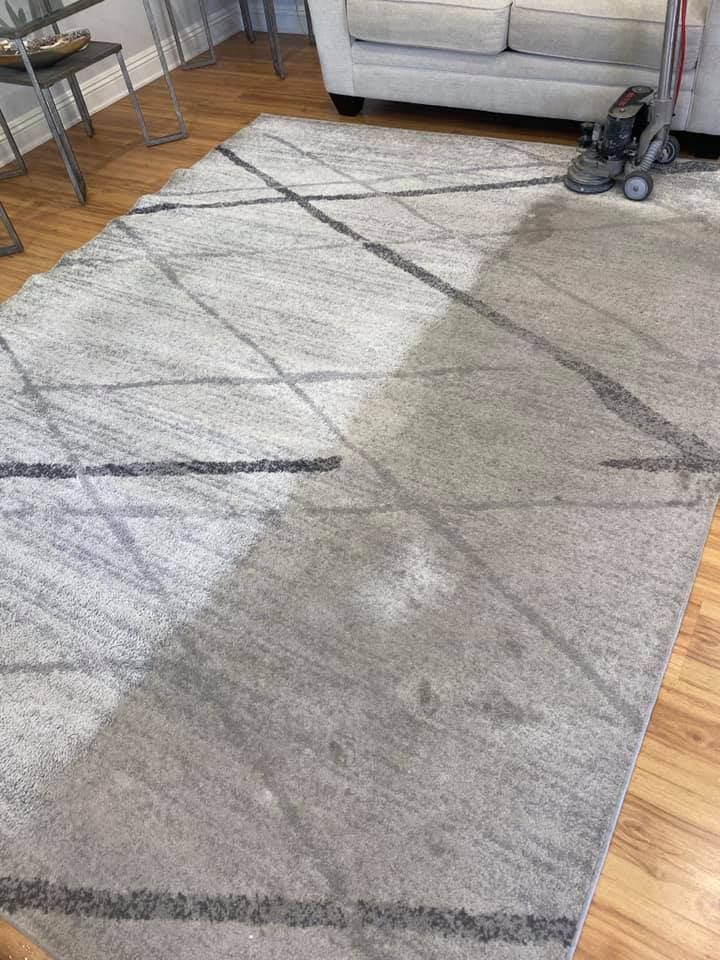 A rug is being cleaned in a living room with a vacuum cleaner.