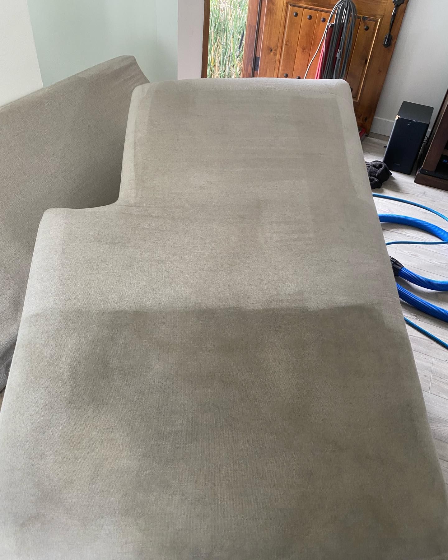 A couch is sitting in a living room next to a vacuum cleaner.