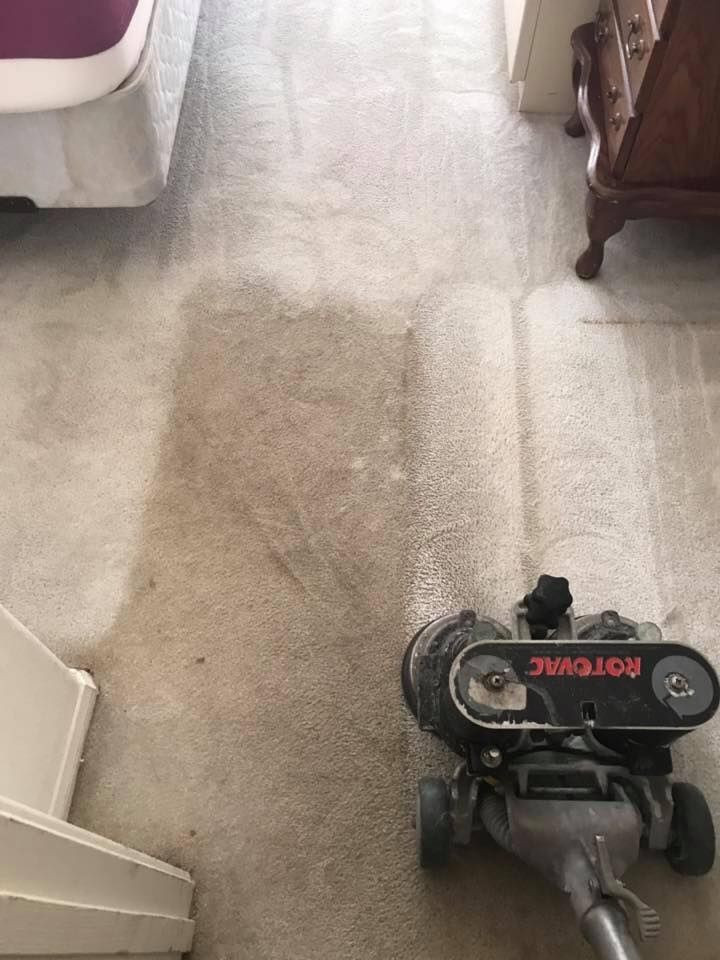 A vacuum cleaner is cleaning a dirty carpet in a living room.