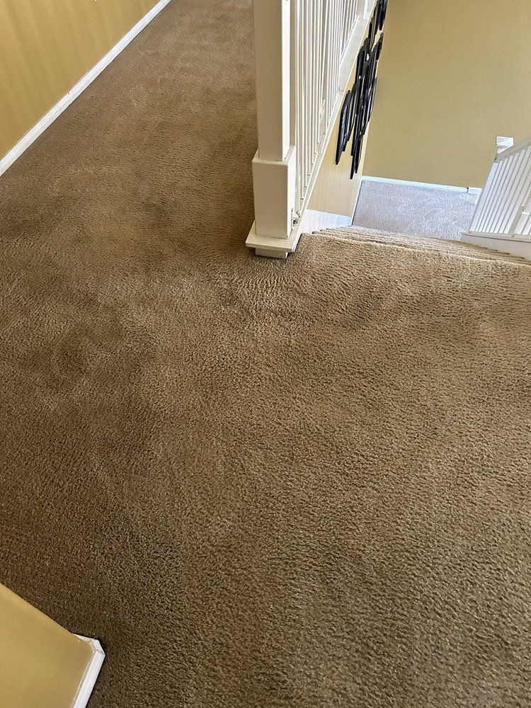 A staircase with a brown carpet and a white railing.