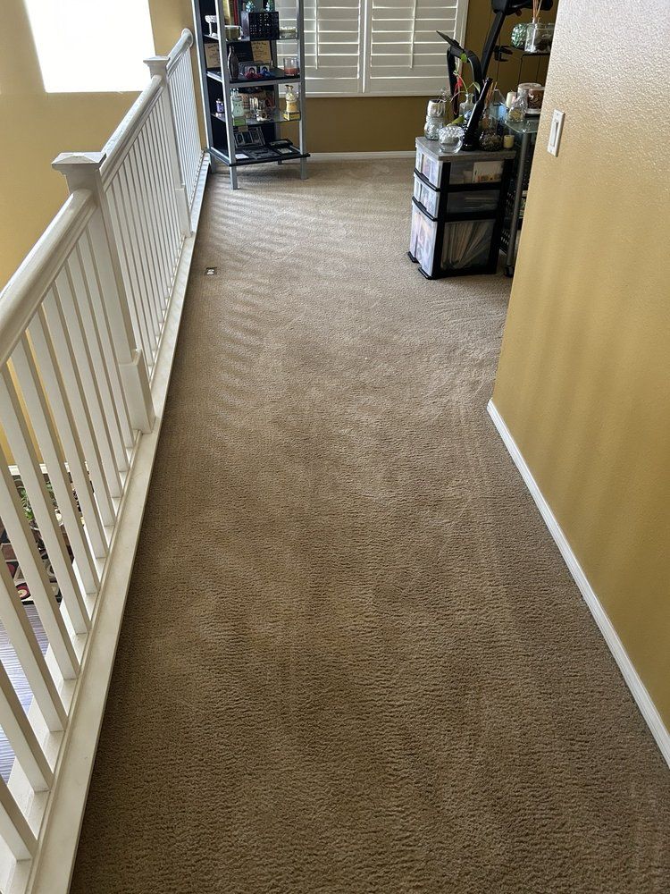A hallway with a railing and a carpeted floor in a house.