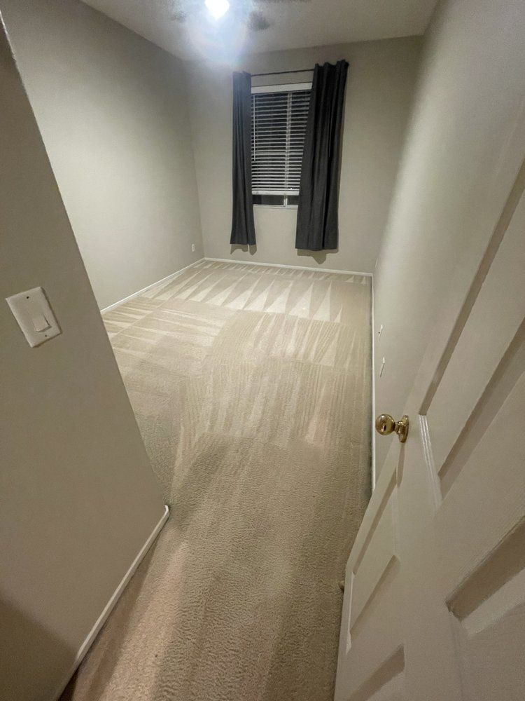 A bedroom with a carpeted floor and a window.