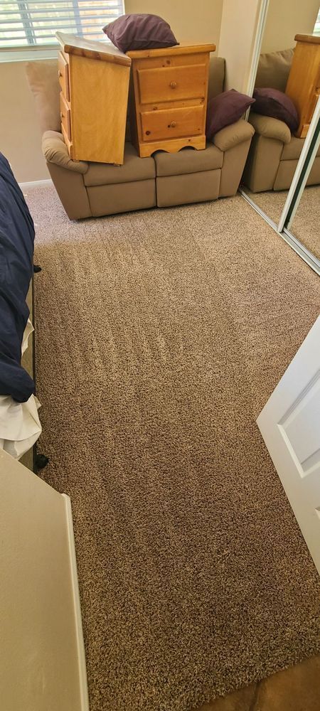 A bedroom with a couch , dresser , nightstand and mirror.