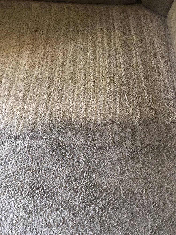 A close up of a carpet in a living room next to a couch.
