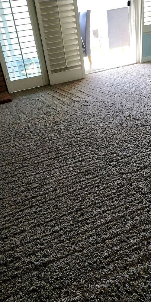 A large carpeted floor in a living room next to a sliding glass door.