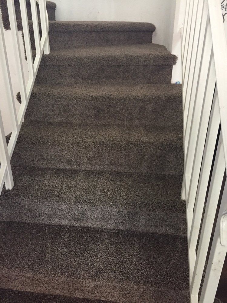 A set of stairs with a carpeted floor and a white railing.