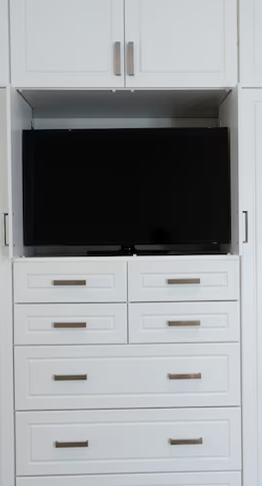 White built-in cabinet with a black TV in a recessed area, drawers below.