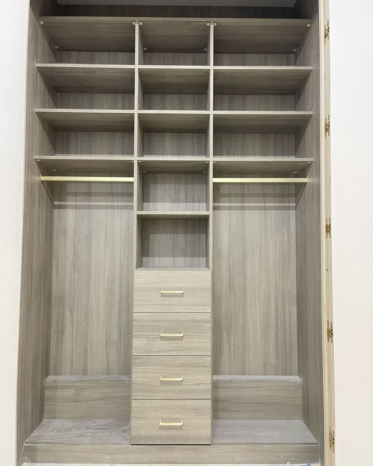 Built-in closet with shelves, drawers, and hanging rods. Gray wood grain finish. Empty, ready for use.