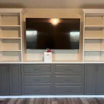Built-in entertainment center with a large TV and cabinets with shelves and drawers.