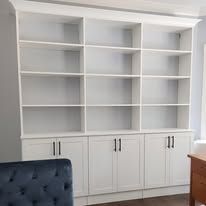White built-in shelving unit with multiple shelves and cabinets in a room.