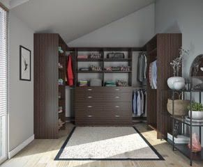 Walk-in closet with dark brown shelving, drawers, and hanging rods; a rug and decorative side table are visible.