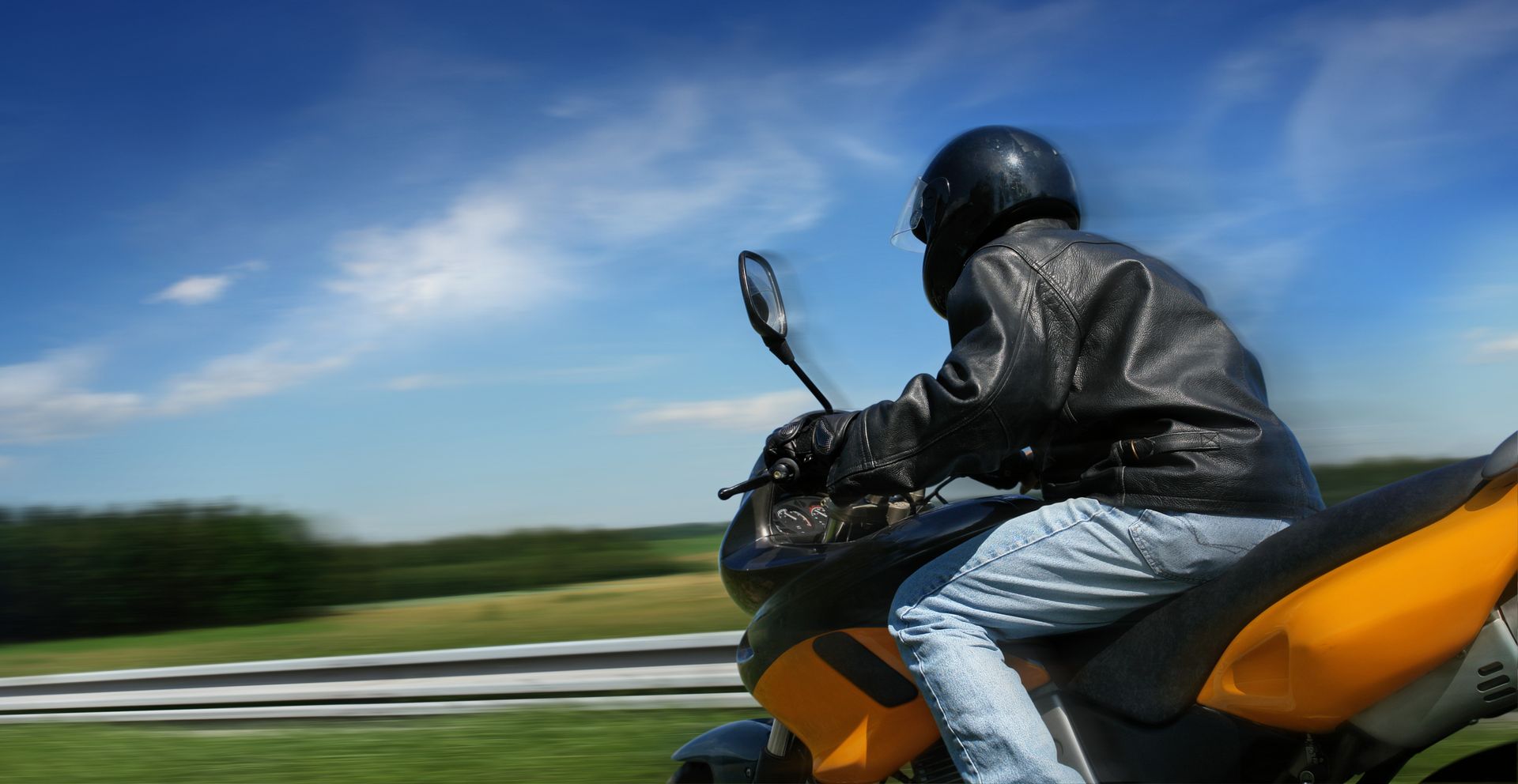 Person riding a motorcycle on a road with a blurred background.