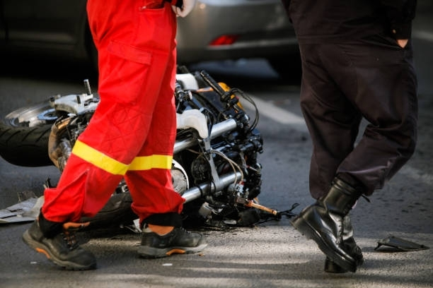 Motorcycle accident scene with two people standing near the fallen bike.