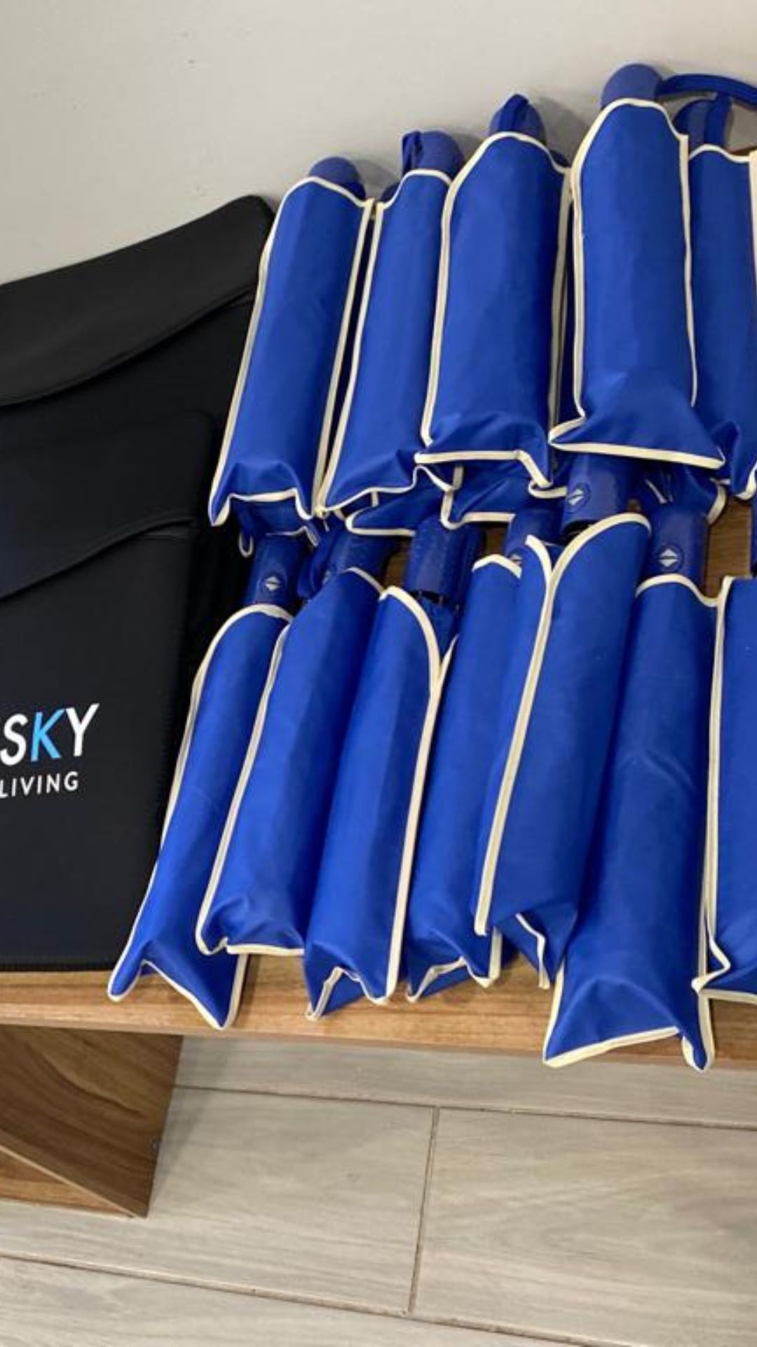 A bunch of blue umbrellas are sitting on a wooden bench.