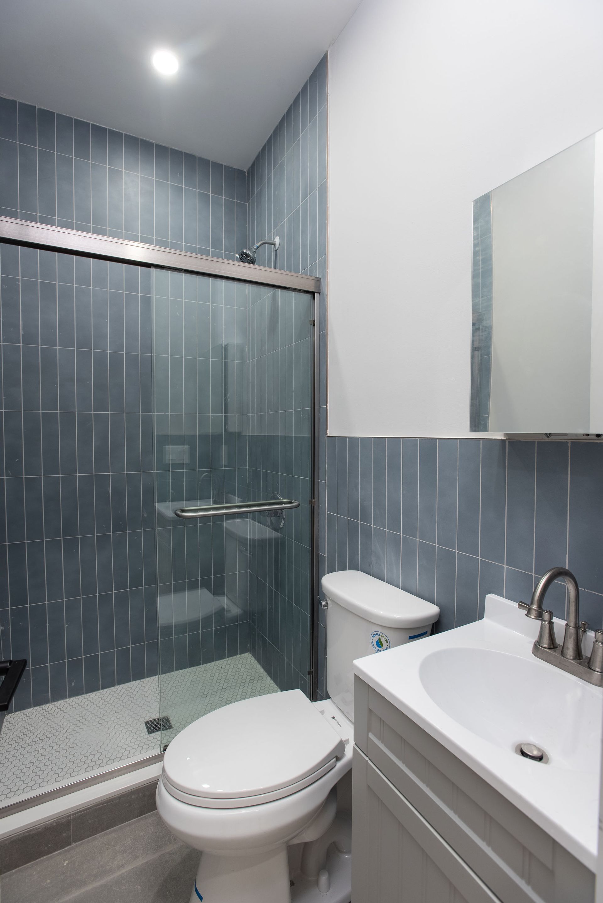 A bathroom with a toilet , sink and shower.