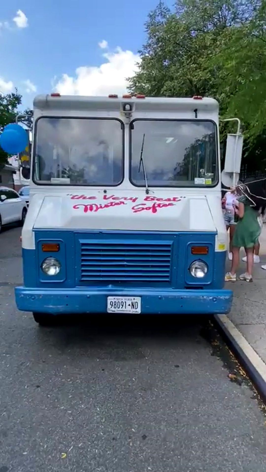 A blue and white food truck is parked on the side of the road.