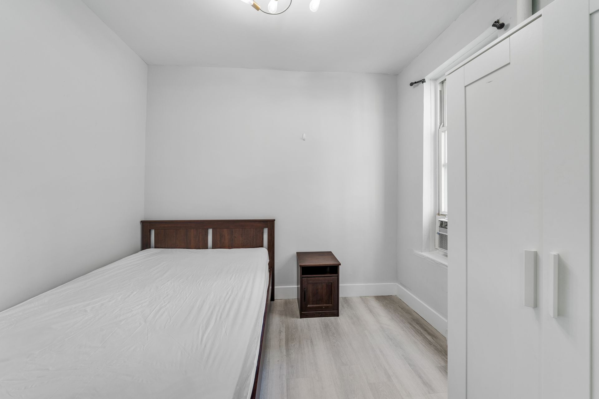 A bedroom with a bed , nightstand , and window.