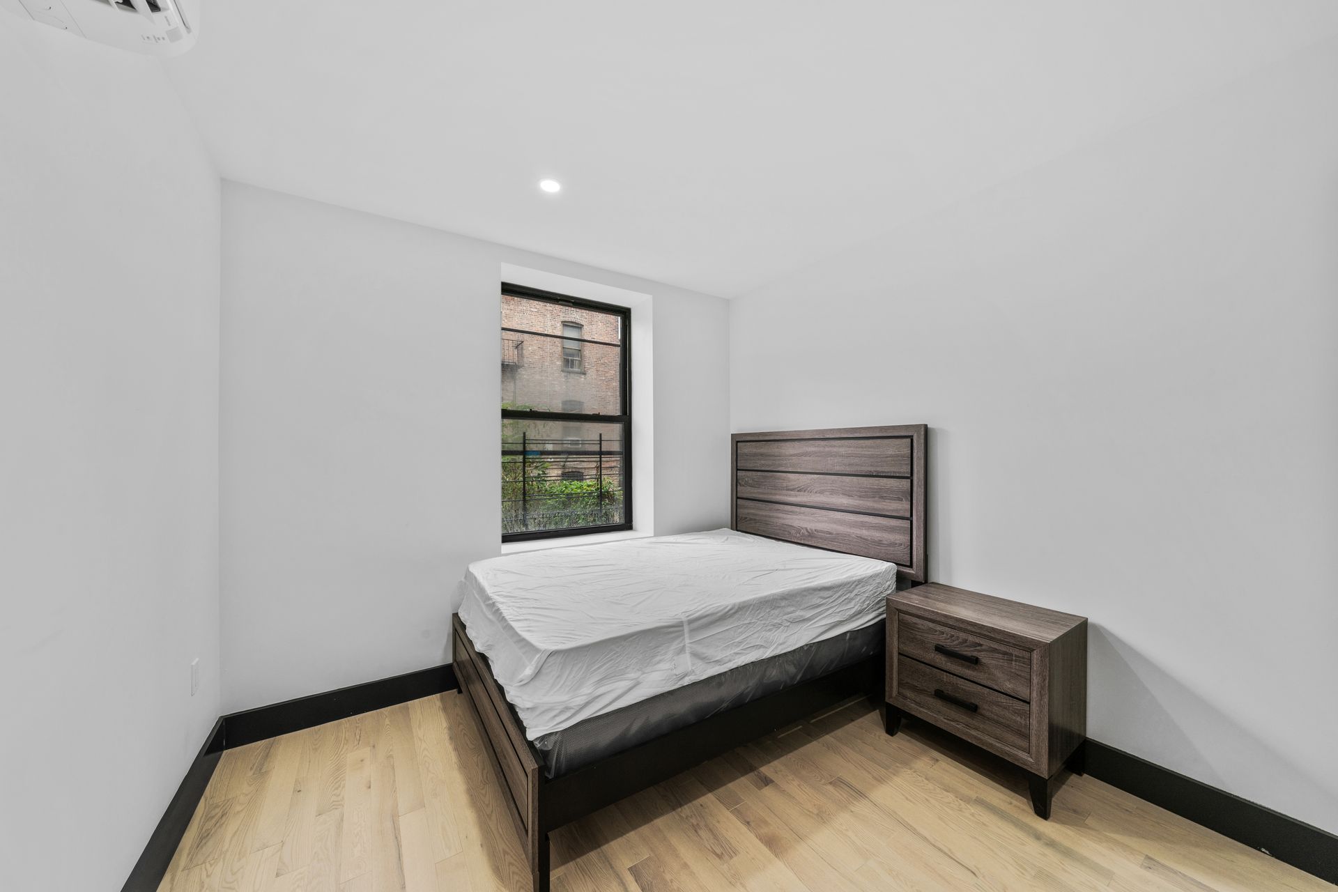 A bedroom with a bed , nightstand , and window.