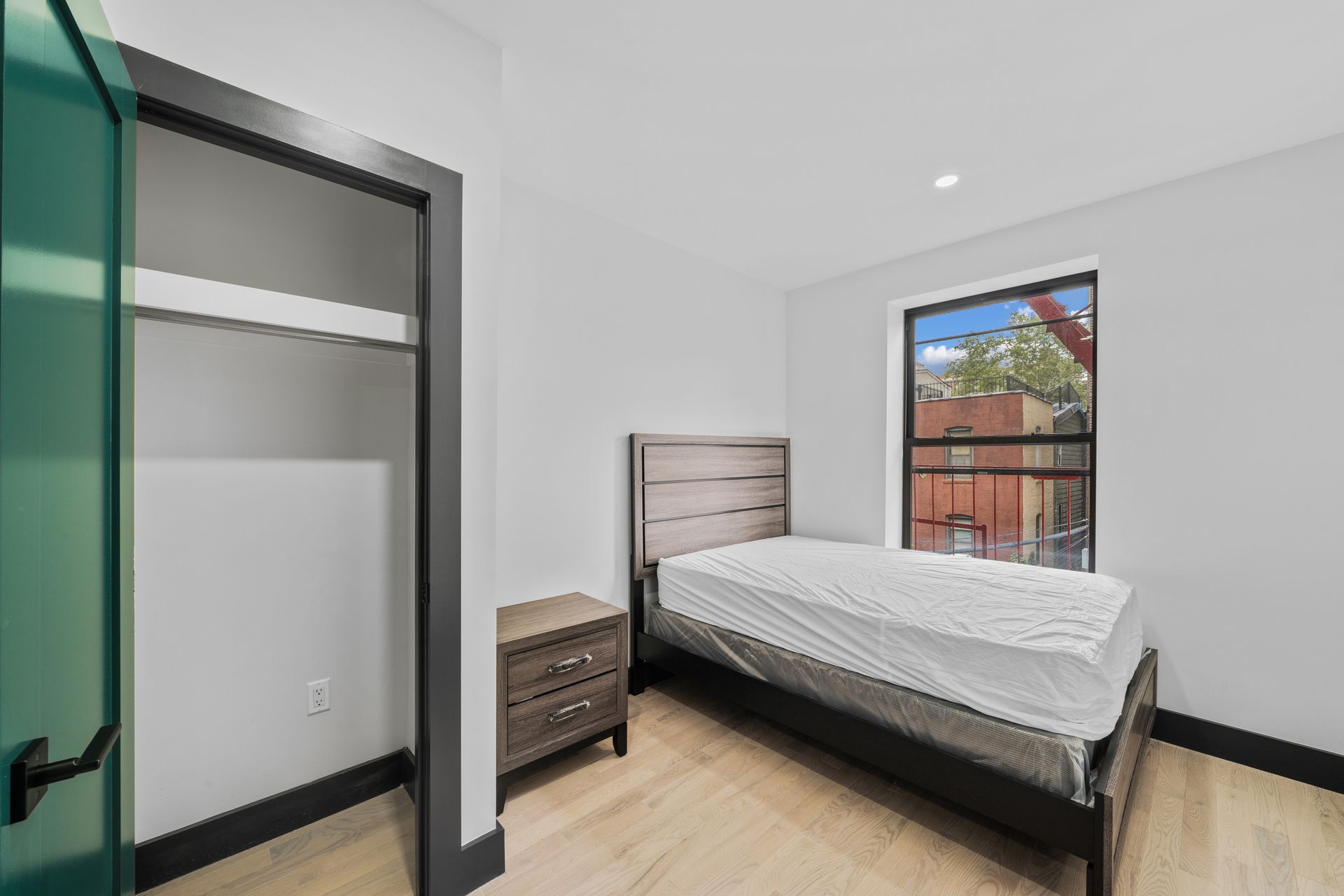 A bedroom with a bed , nightstand , closet and window.