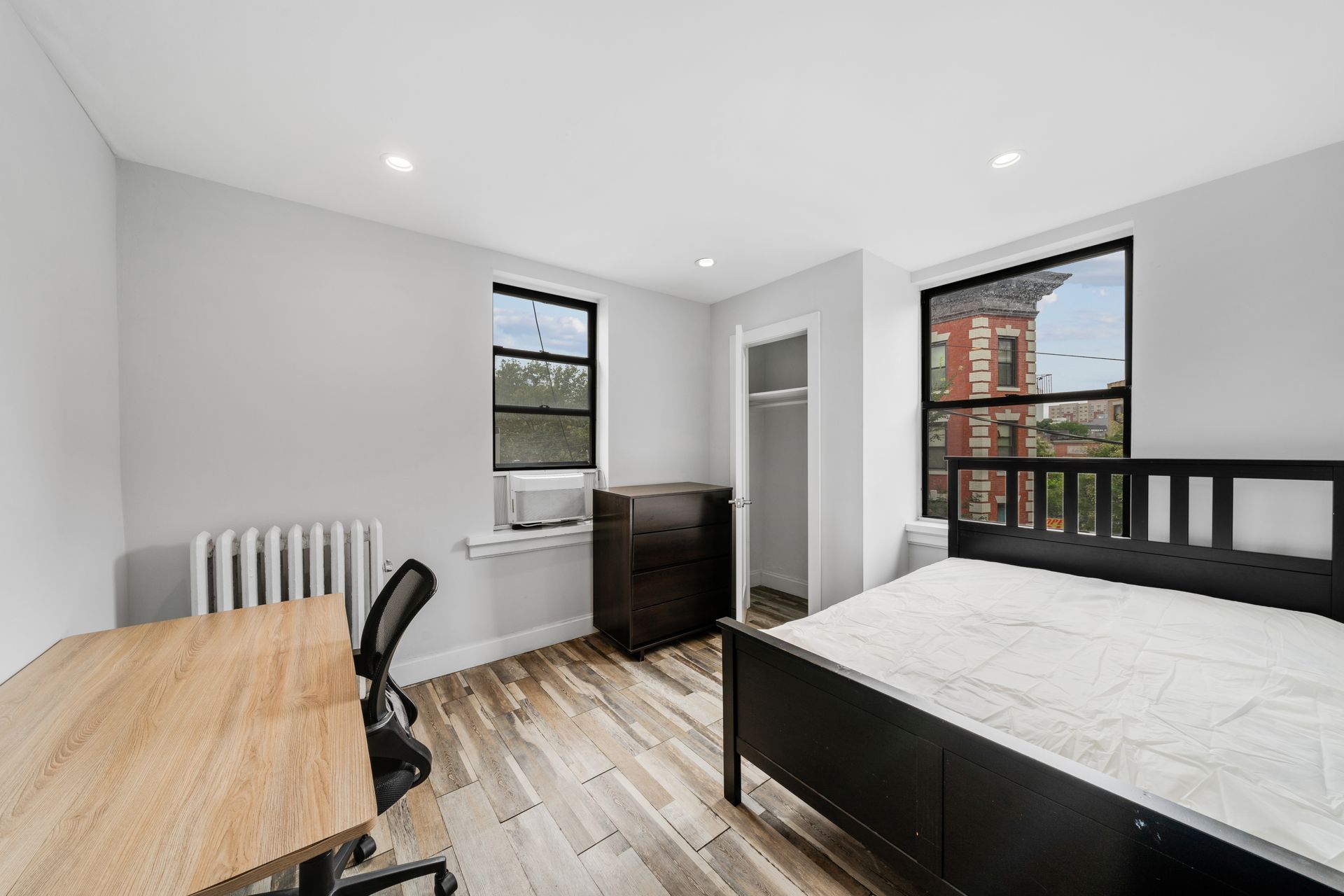 A bedroom with a bed , desk , chair and window.