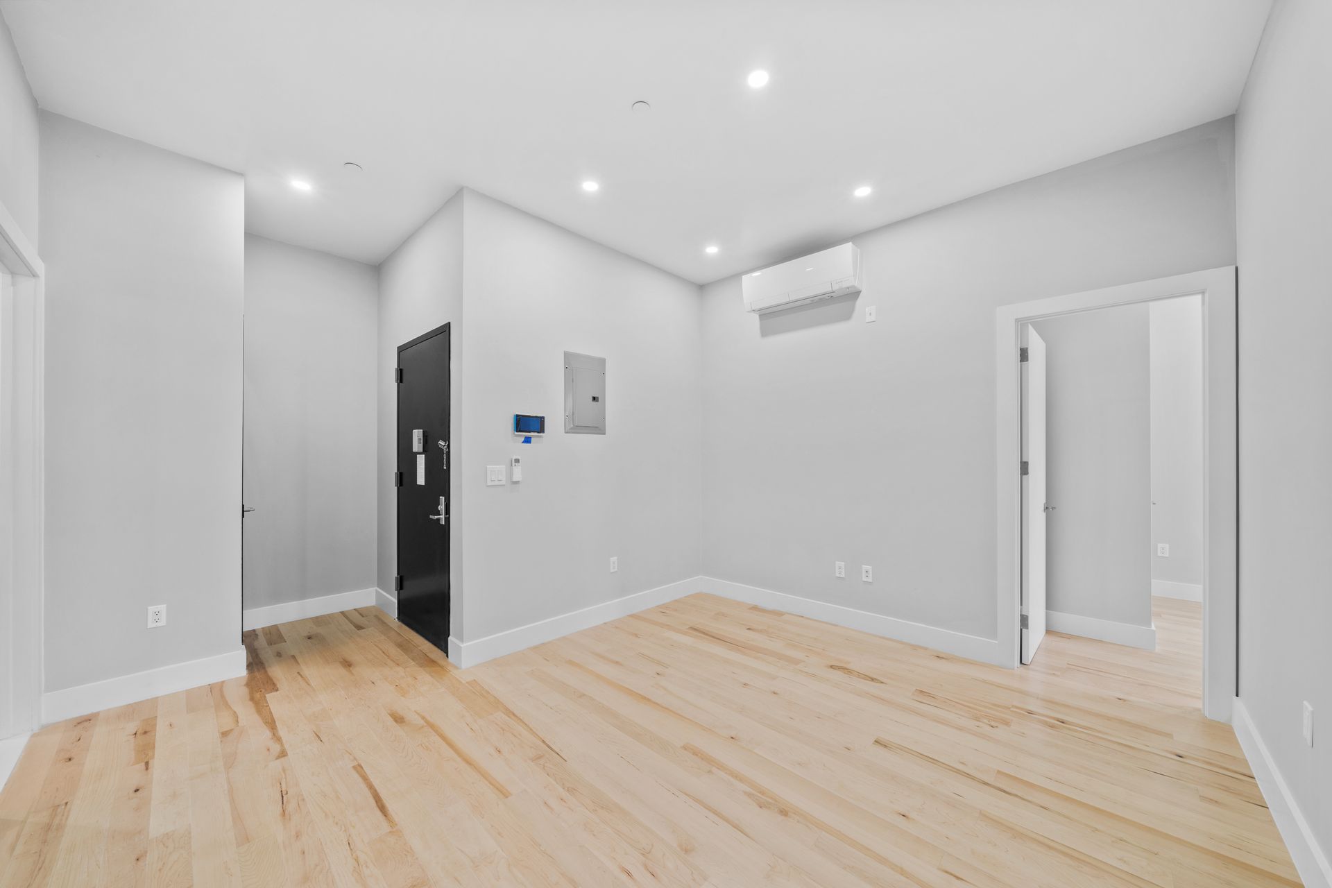 An empty living room with hardwood floors and white walls.