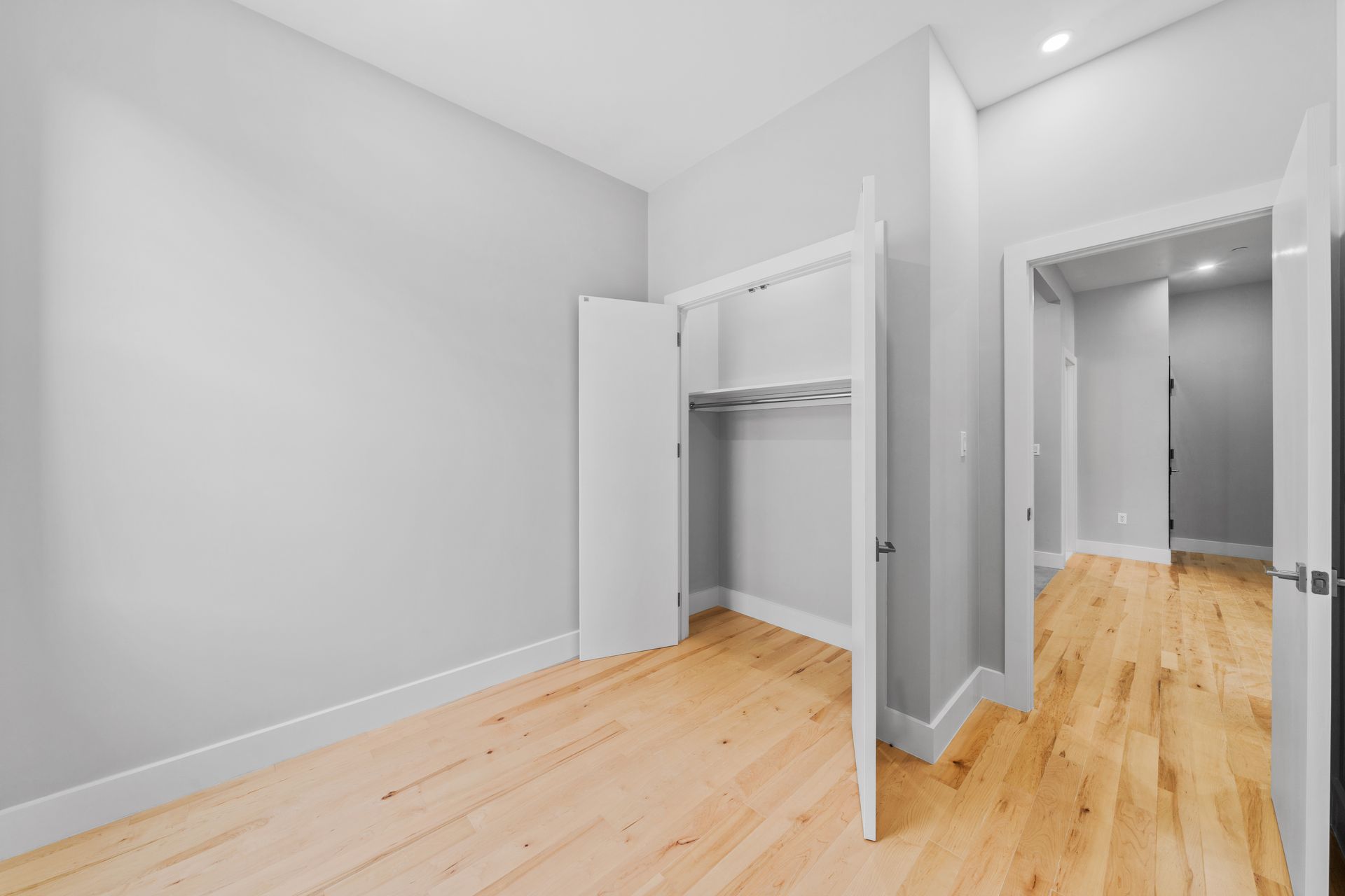An empty bedroom with hardwood floors and a closet.