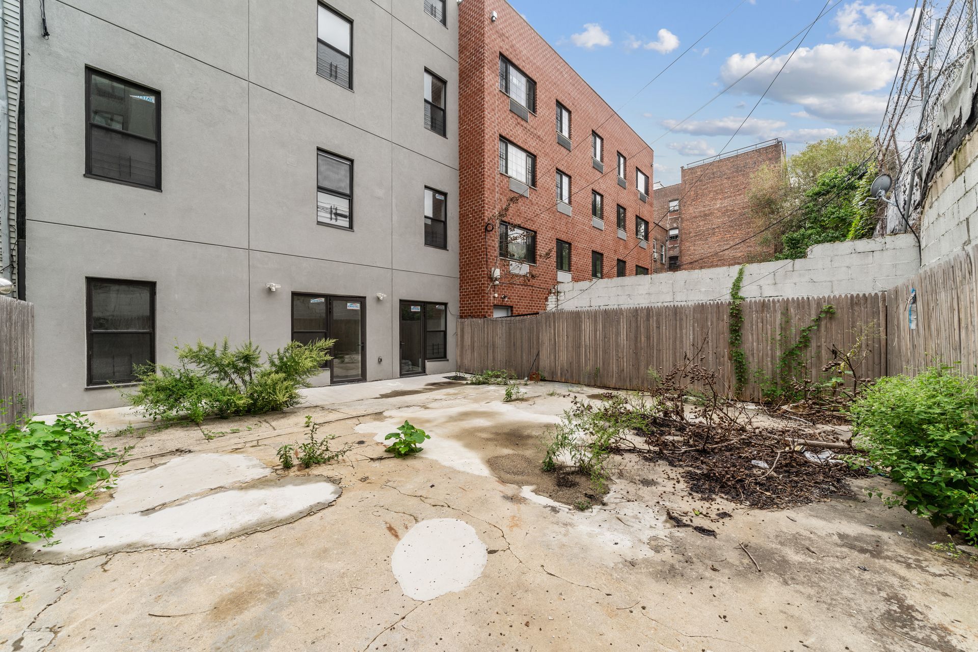 A backyard with a fence and a building in the background
