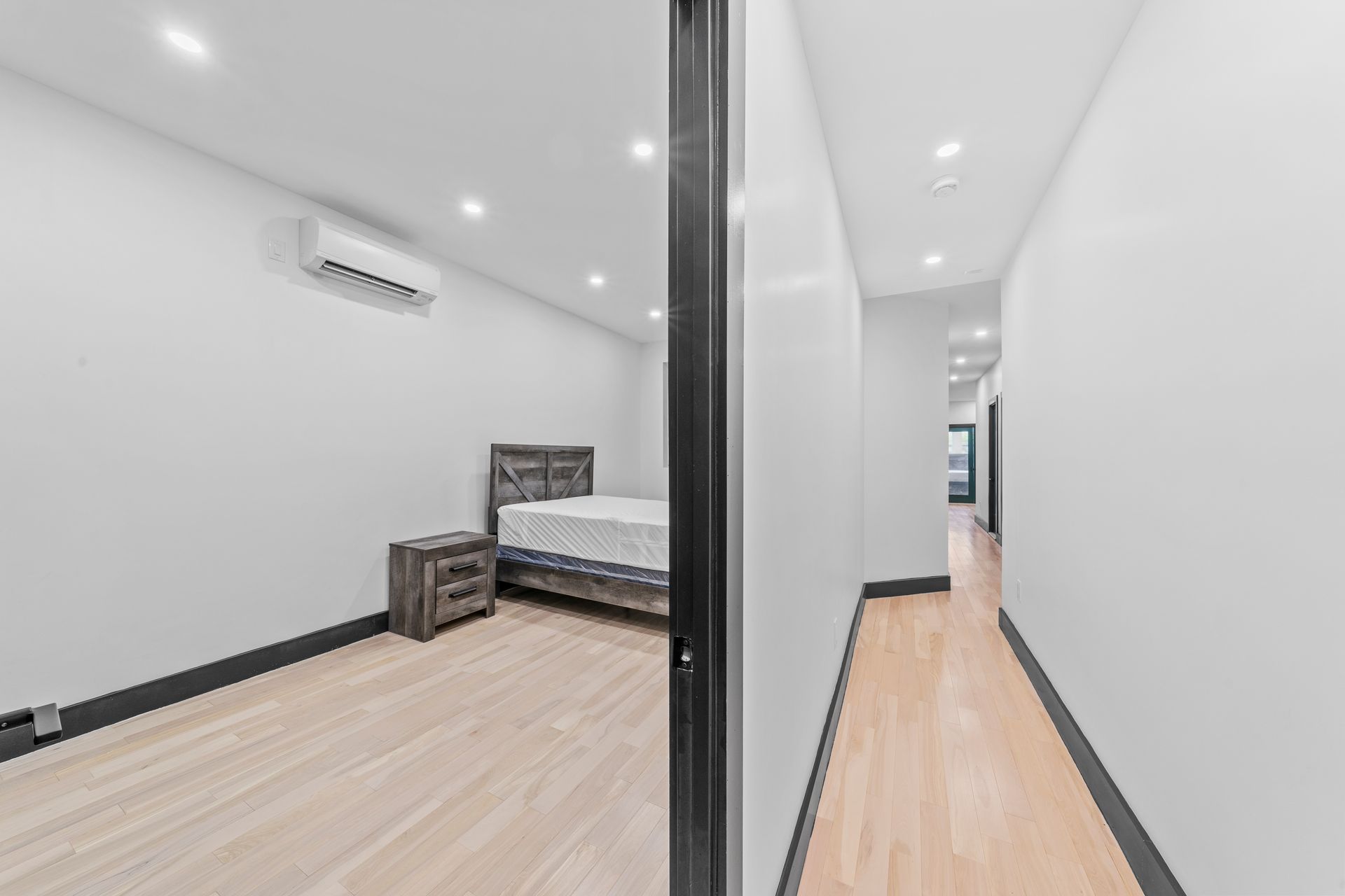 A bedroom with a bed , nightstand , and air conditioner.