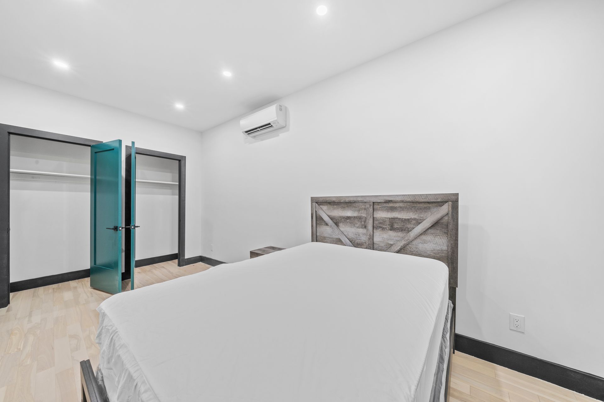 A bedroom with a bed , closet , and air conditioner.