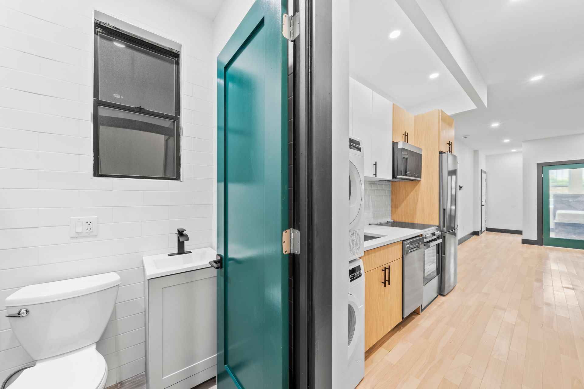 A bathroom with a toilet , sink , refrigerator and microwave.